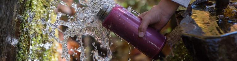 Enfant remplissant sa gourde d'eau à la fontaine
